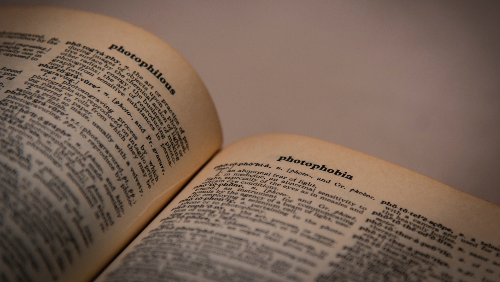 Un dictionnaire anglais est ouvert aux pages « photophilous » et « photophobia ».