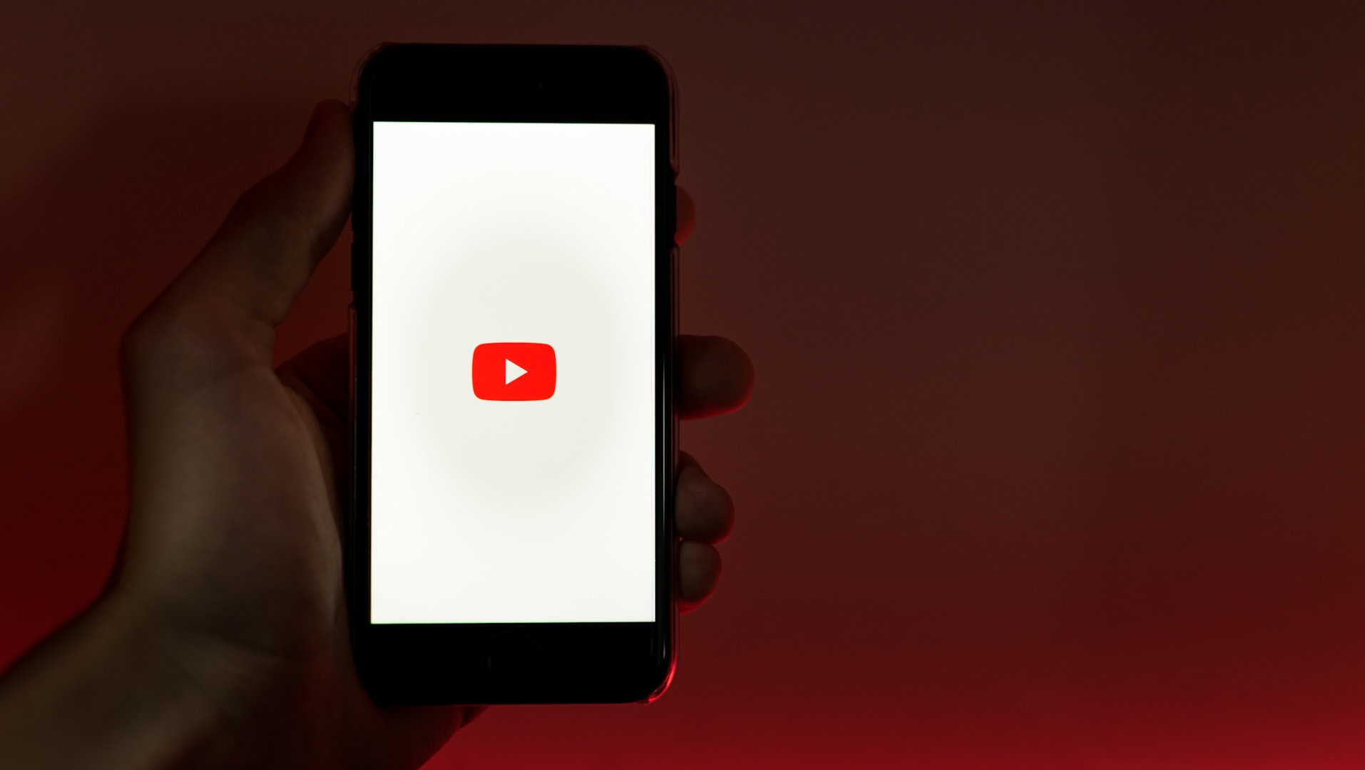 Une personne tient un téléphone portable affichant le logo de Youtube.