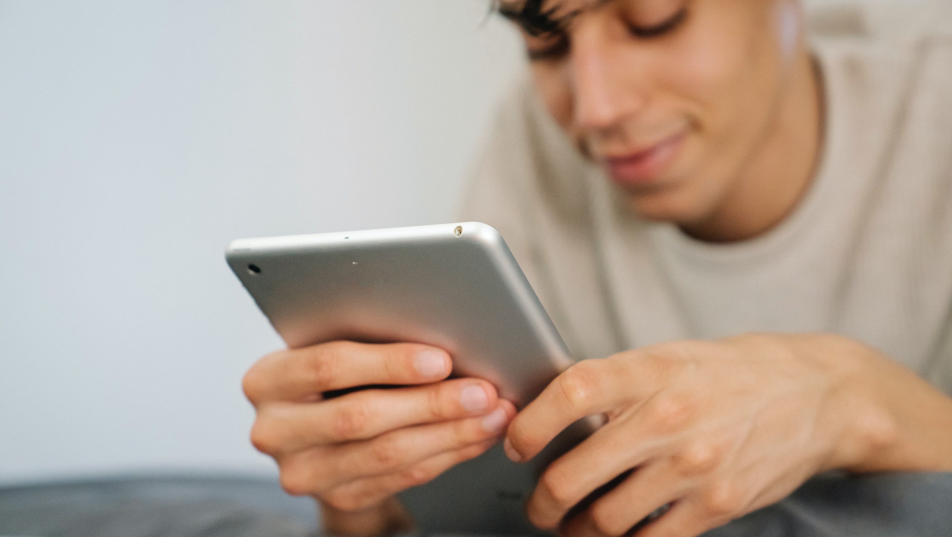 Un homme regarde en souriant l’écran d’une tablette.